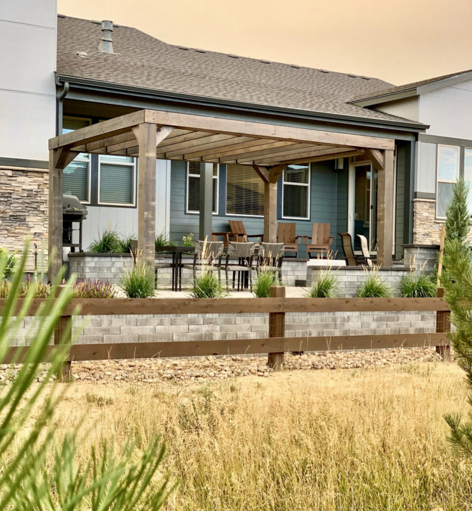 Paver patio with fire pit and pergola and outdoor dining in a Timnath backyard by Summit Outdoor Living