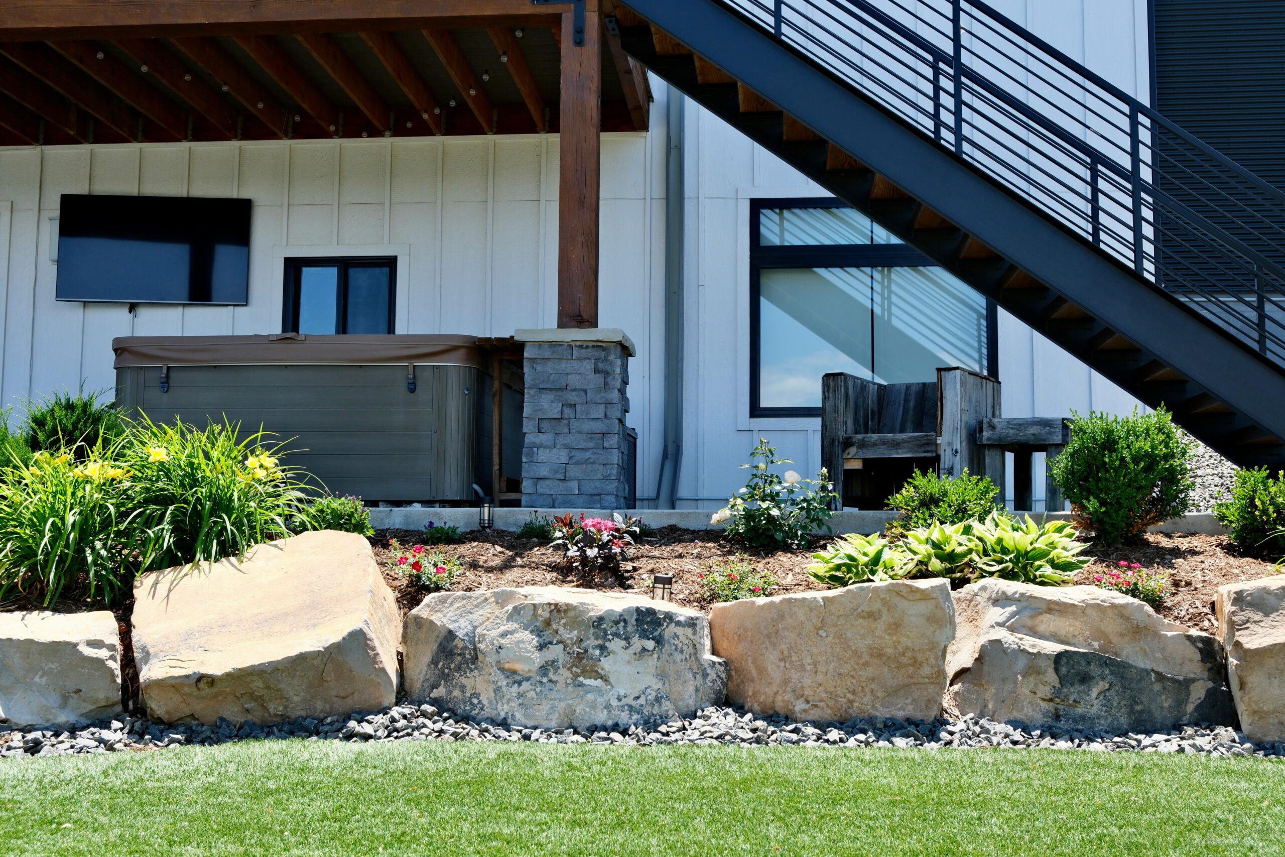 boulder wall, landscaping bed with plantings, and hot tub landscaping in Windsor, CO